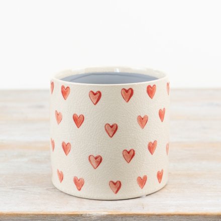 A chic cream planter adorned with an array of dainty painted red hearts.