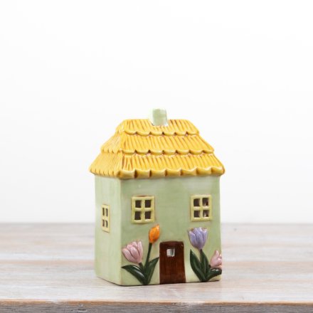 Delightful green candle shaped like a floral house with a charming design.