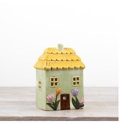 Delightful green candle shaped like a floral house with a charming design.