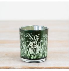 Bring whimsy home with this green glass candle holder adorned with delicate rabbits and floral details.