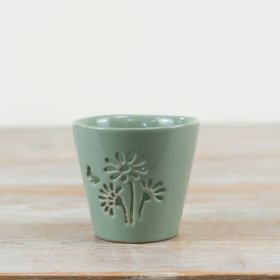 Discover this sage green glazed candle holder with a delicate floral cut-out design.