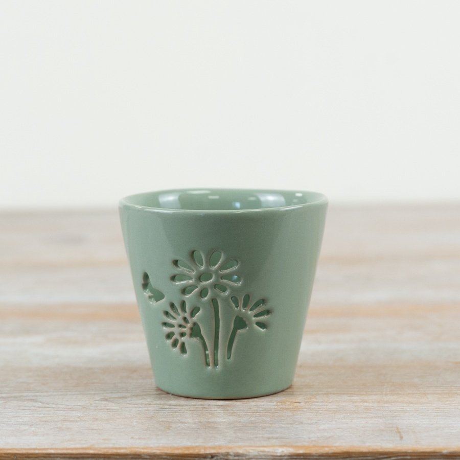 Discover this sage green glazed candle holder with a delicate floral cut-out design.