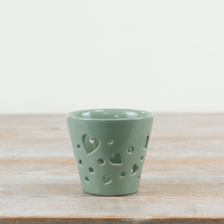 This delicate candle holder showcases mini heart cutouts with a smooth, simple glazed finish.