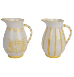 A mix of 2 dolomite jugs, each with a yellow painted design. 
