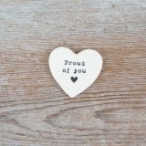 A simple yet meaningful heart token with the words 'proud of you' embossed in black with a dainty heart underneath