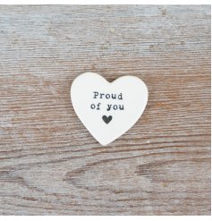 A delicate heart token embossed with "proud of you" in black, featuring a small heart below.