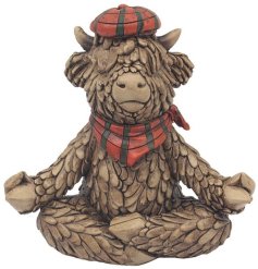 A charming rustic Highland cow ornament, part of the Hughie collection - sat in a yoga pose whilst wearing a tartan scar