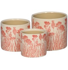 A set of 3 planters each with a stylish poppy and poppy seed design in a subtle red hue. 