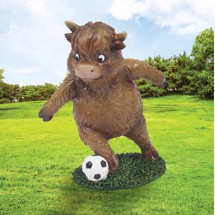 A playful cow statue enjoying a game of football.