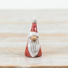 A small ceramic Santa finished in warm red tones with a simple, modern silhouette.