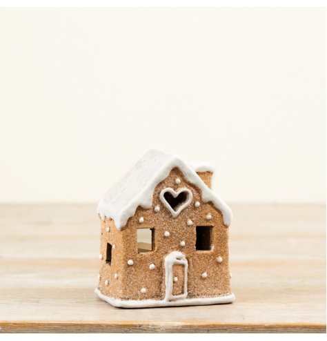 A festive gingerbread house tealight holder with icing-style detailing and cut-out windows that create a warm glow when 
