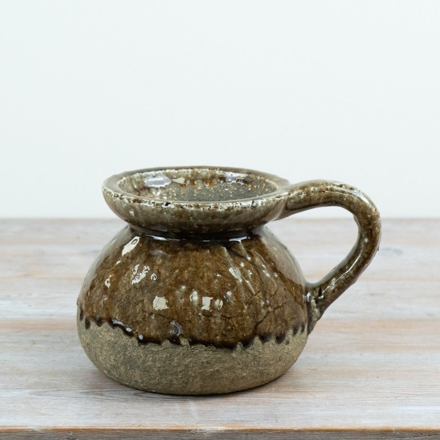 A characterful ceramic jug featuring a rich, reactive glaze in earthy brown and stone tones