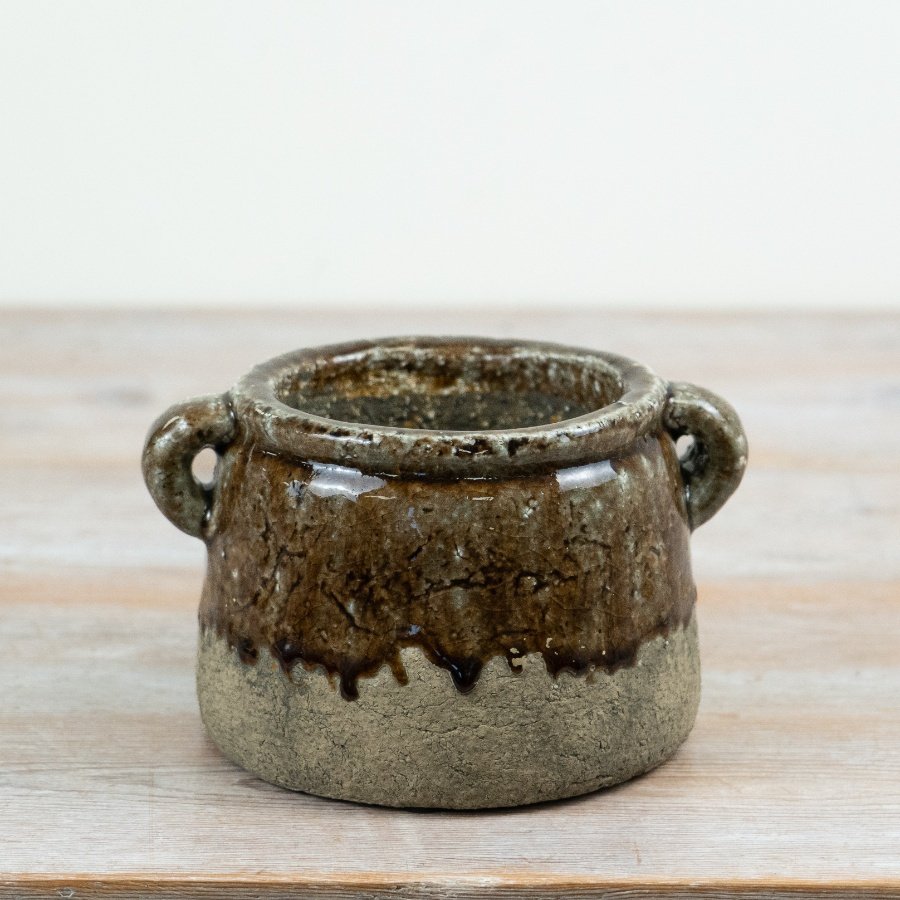A rustic ceramic planter featuring a rich, reactive glaze in layered earthy browns and stone tones.