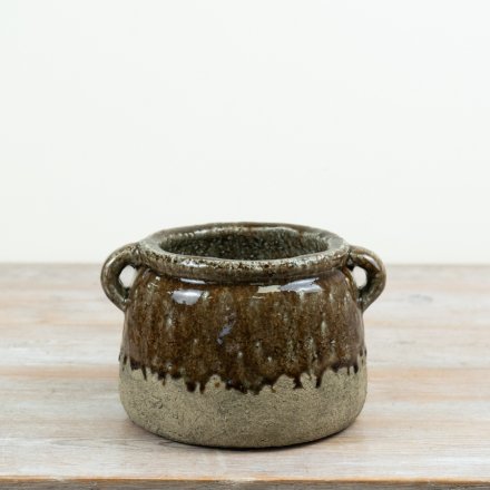 A decorative stoneware planter featuring a deep brown reactive glaze and natural textured lower half.