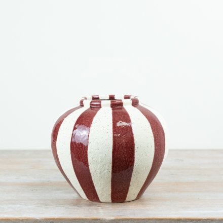 A statement ceramic vase featuring bold red vertical striping set against a softly speckled cream base