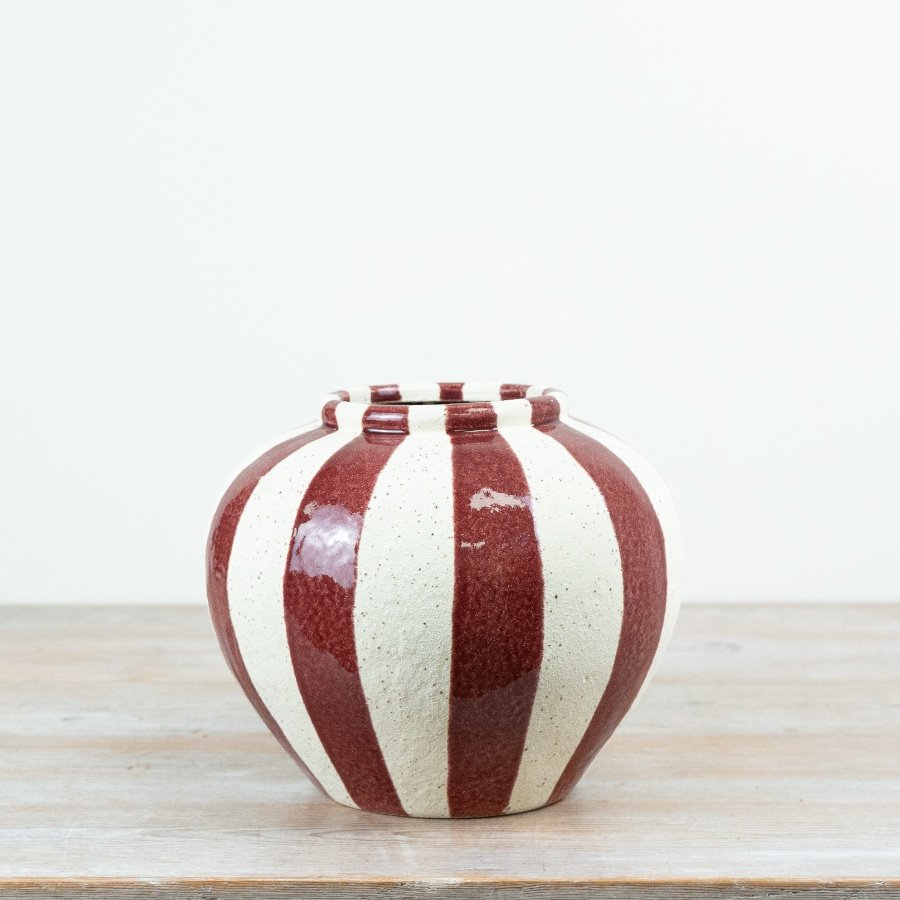 A bold statement vase featuring wide vertical stripes in rich red set against a softly speckled cream base.