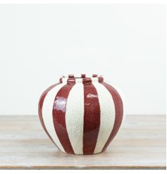 A statement ceramic vase featuring bold red vertical striping set against a softly speckled cream base