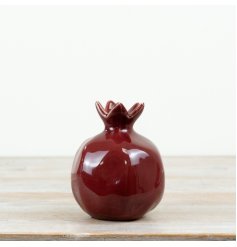 A bold ceramic pomegranate finished in a deep red glossy glaze
