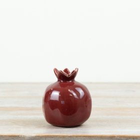 A decorative ceramic pomegranate finished in a bold deep red glaze
