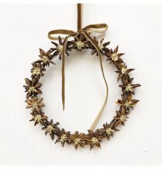 This wreath showcases natural star anise pods with delicate gold centers for a warm, festive touch.