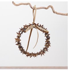 This wreath showcases natural star anise pods with delicate gold centers for a warm, festive touch.