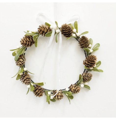 A delicate festive wreath decorated with pinecones, mistletoe leaves and small white berries