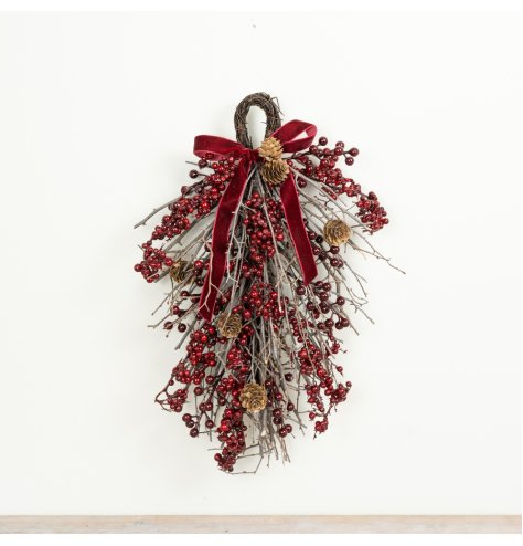 A traditional festive door hanging featuring red berries, twigs and pinecones