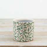 A decorative ceramic planter featuring a delicate all-over foliage design with green leaves and red berry accents.