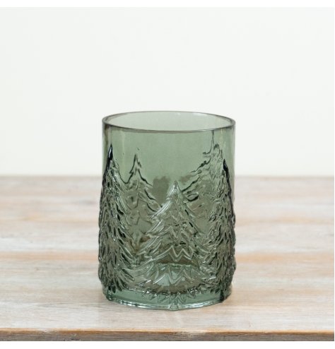 A stylish green glass featuring embossed Christmas trees that beautifully enhance flickering candlelight.