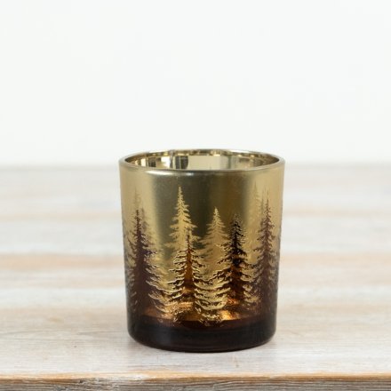 Gold-finished glass tealight holder with intricate tree design, casting a warm, glowing candlelight.