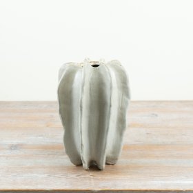 Natural stoneware and designed with a striking sculptural form featuring deep vertical ridges. 