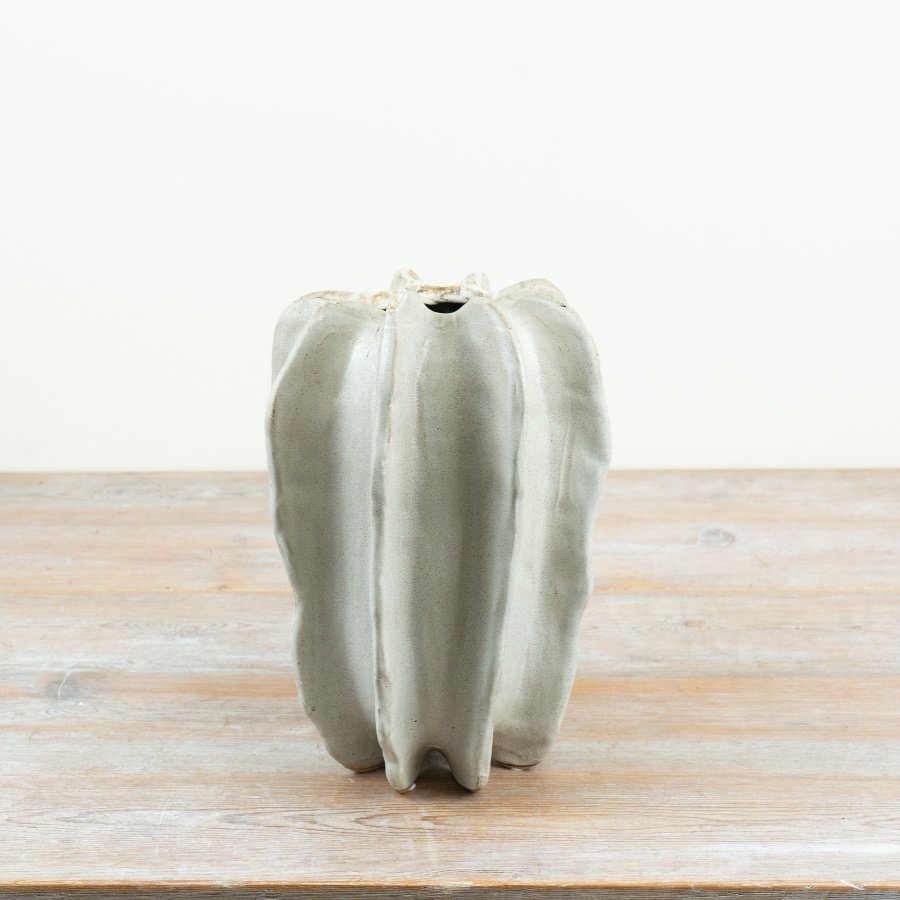 Natural stoneware and designed with a striking sculptural form featuring deep vertical ridges. 