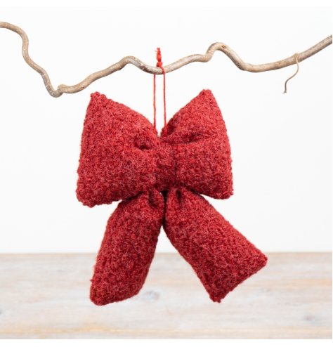 A festive red bow decoration made from soft bouclé fabric and complete with a hanging loop. 
