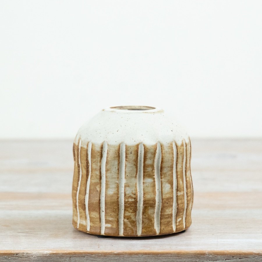 Designed with a soft earthy palette, this 10cm ceramic vase features engraved vertical stripes and a beautifully rustic 