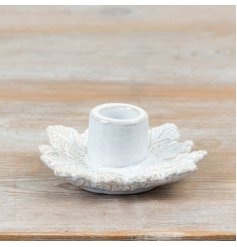 A decorative ceramic candle holder featuring a detailed leaf design and a soft neutral finish.