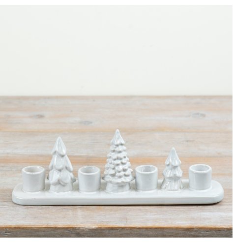 A festive ceramic candle holder featuring decorative Christmas trees and designed to hold four tall candles