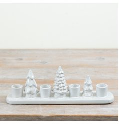 A ceramic candle holder featuring decorative Christmas tree detailing and designed to hold four tall candles.