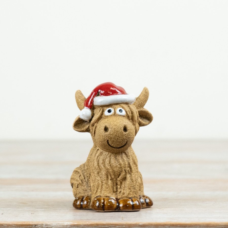 Highland cow ornament features textured detailing and a festive red hat for seasonal charm.