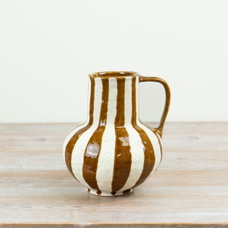 This ceramic jug-style vase features a softly rounded silhouette with an integrated handle and a hand-finished stripe