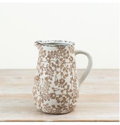 A rustic stoneware jug with an all-over botanical design in warm brown tones on a soft, 
