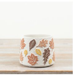 Cement planter with a textured surface and raised leaf design in autumn colours.