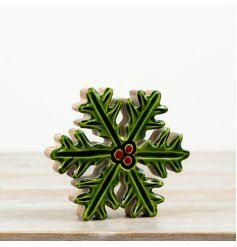 A festive mango wood and enamel holly decoration with glossy green leaves and red berry detail.