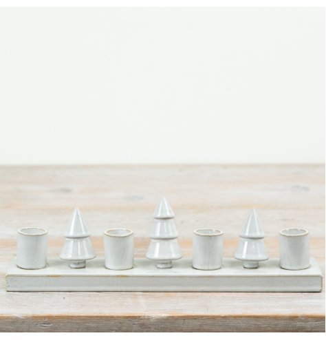 Create a warm festive centrepiece with this charming ceramic candle holder featuring decorative Christmas tree shapes.