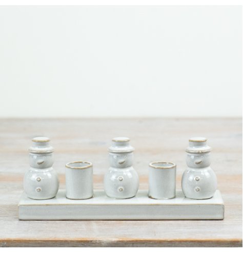 Decorative set with three glazed ceramic snowmen and two candle holders for a festive touch.