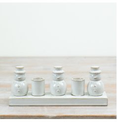  Designed as a decorative arrangement, the piece features three glazed ceramic snowmen with two candle holders