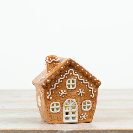 Gingerbread house features charming icing-style detailing and a warm internal glow for a cosy festive finish. 