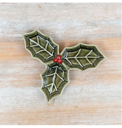 Festive ceramic dish shaped like three layered holly leaves with raised details and a shiny green glaze.