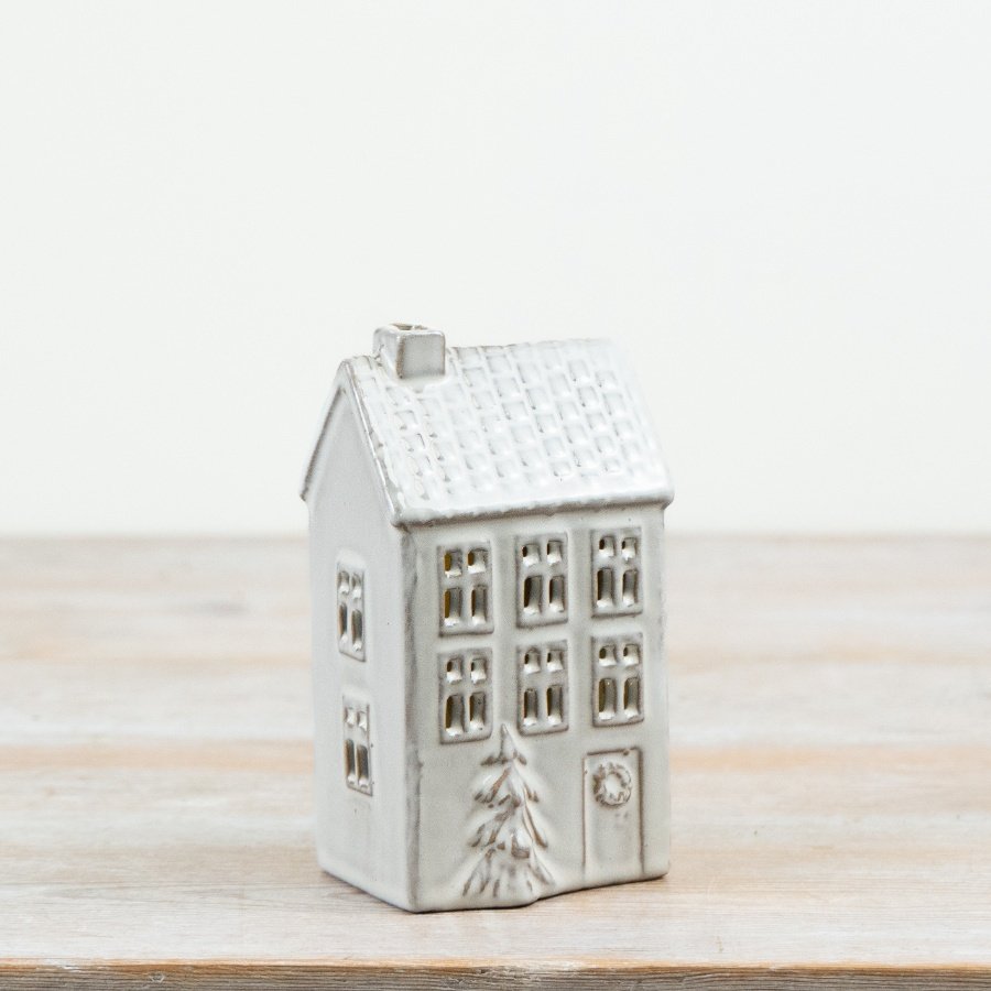 Decorative ceramic house featuring a natural glaze finish, window cut-outs and a raised 3D Christmas tree detail.