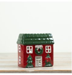 Ceramic tealight holder designed as a festive red house with Christmas trees and a wreath detail.