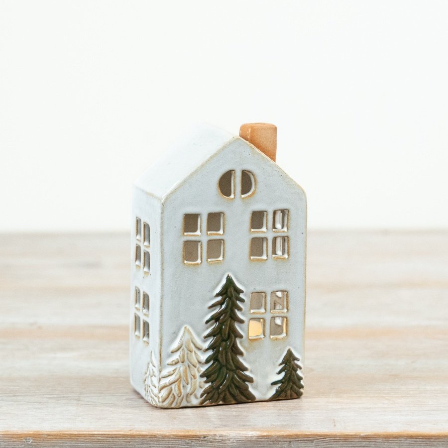 Crafted in a tall townhouse design, this decorative piece features delicate cut-out windows and hand-finished fir tree 
